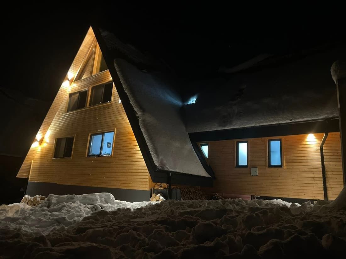 Cabana luminată noaptea, în zăpadă